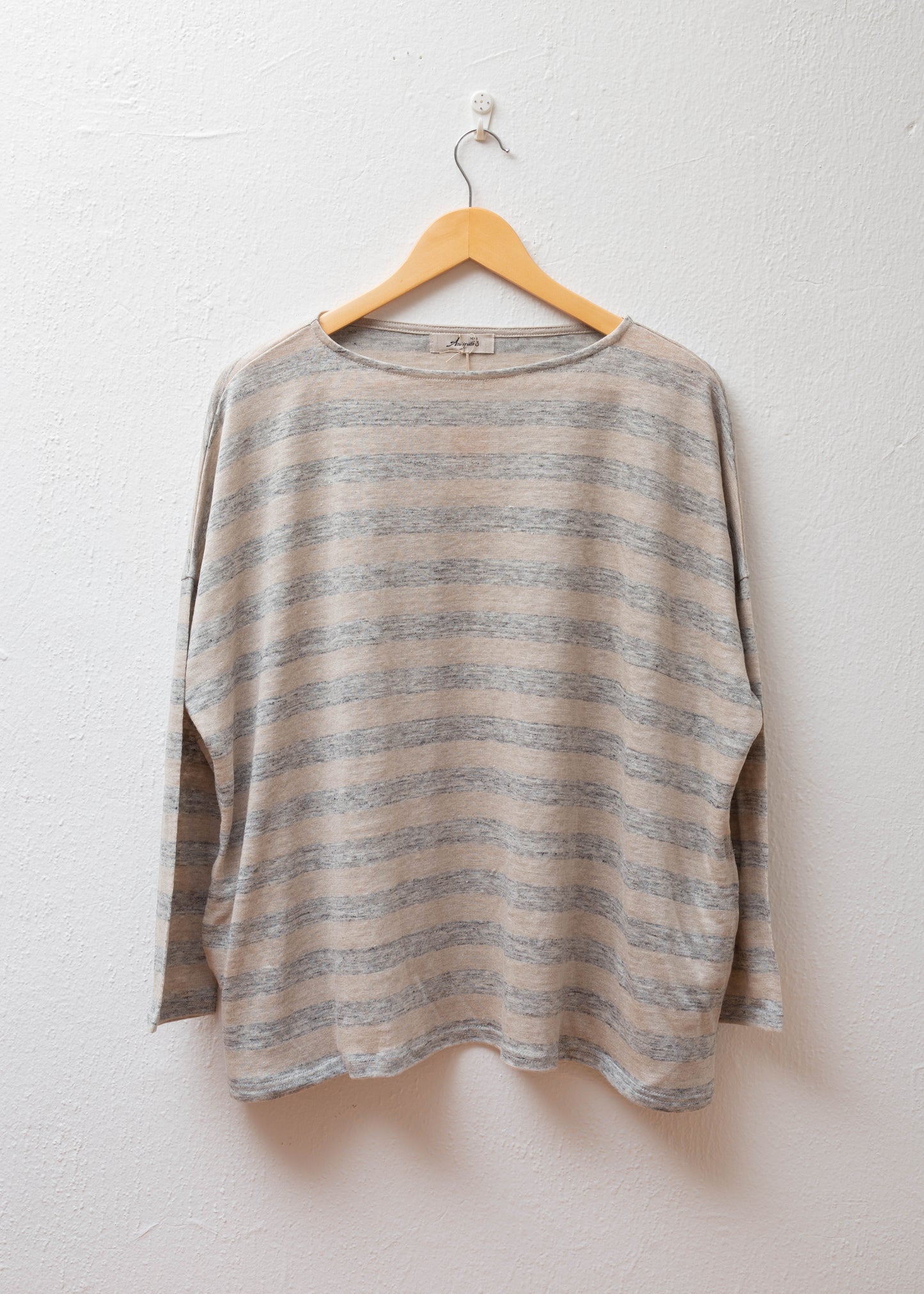 Linen Pullover in Natural/Grey hanging on a white wall