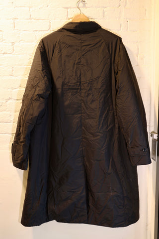 Black coat hanging on a hook against a white brick wall.