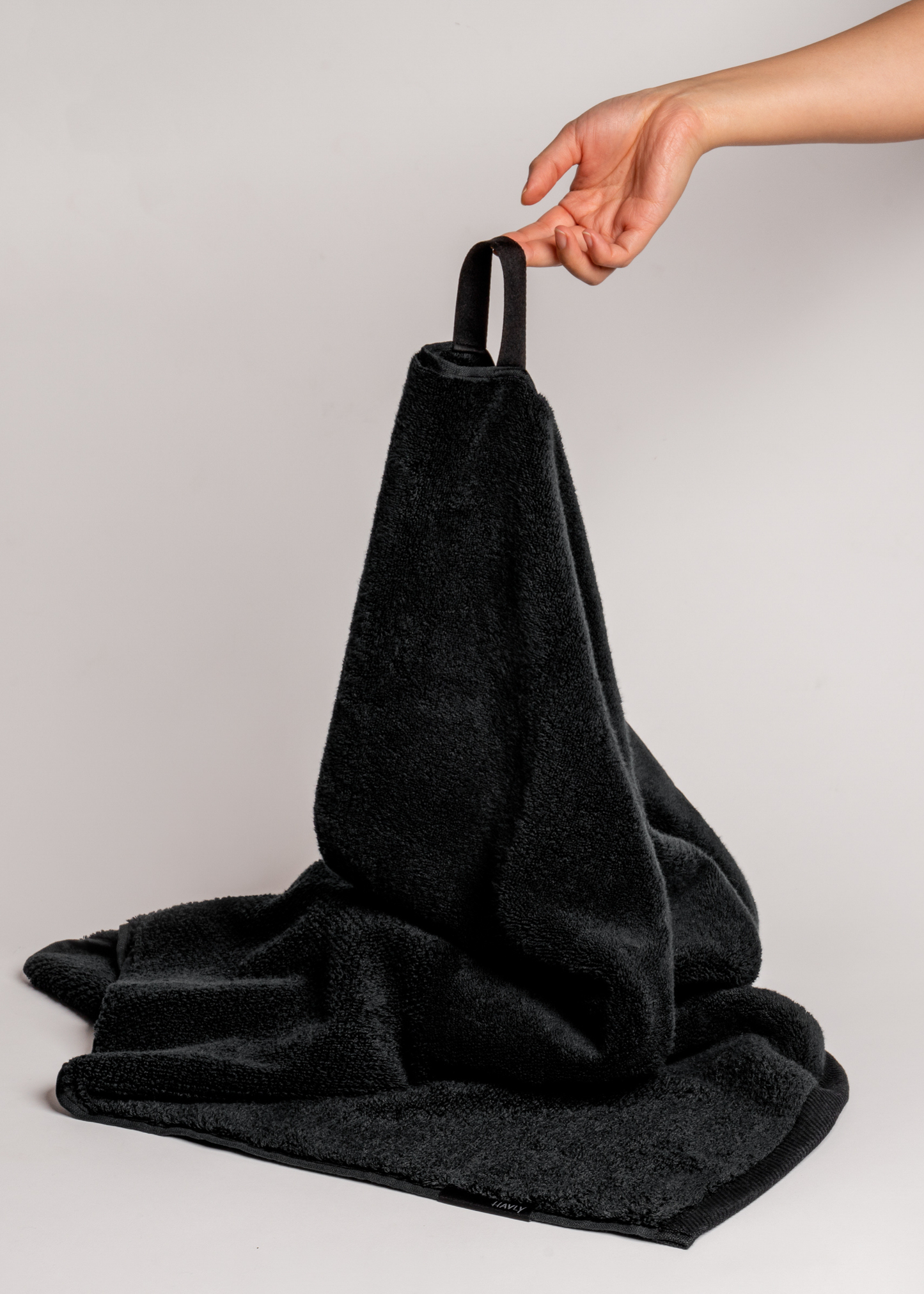 hand holding black bath towel by loop