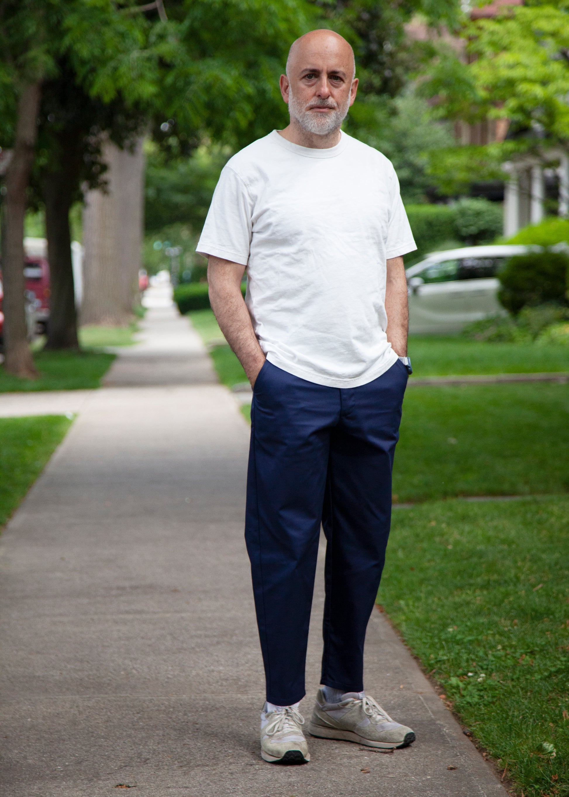 Model wearing white t-shirt, lightweight danver pants in color navy and white/grey sneakers. Outdoors 