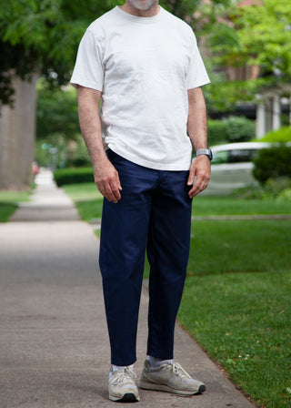 Model wearing white t-shirt, navy lightweight danver pants and white/grey sneakers 