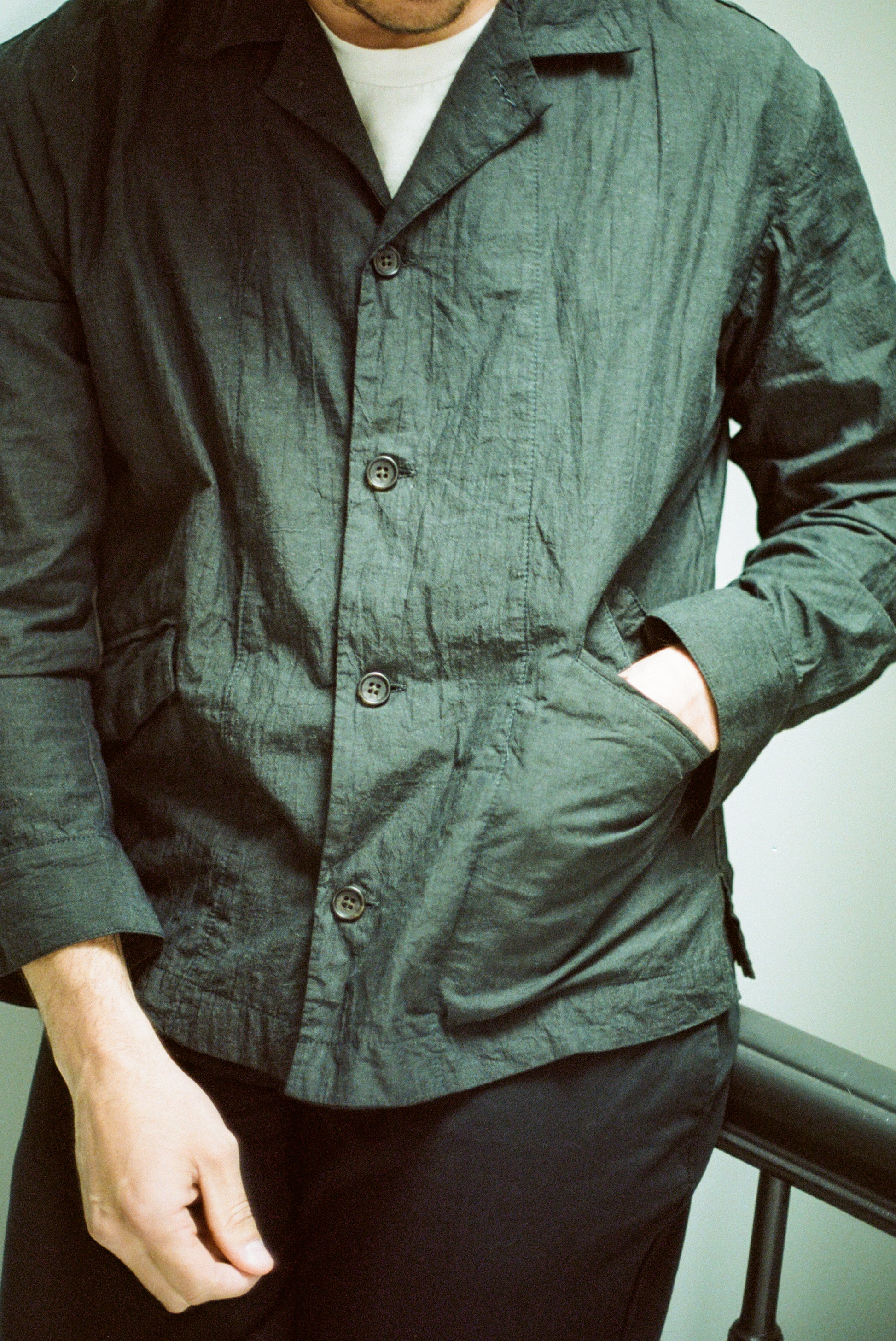 Close up of male model wearing dark green painter shirt and black pants