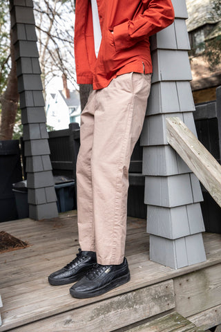 side shot of model wearing painter jacket with white t-shirt, maker pants and sneakers