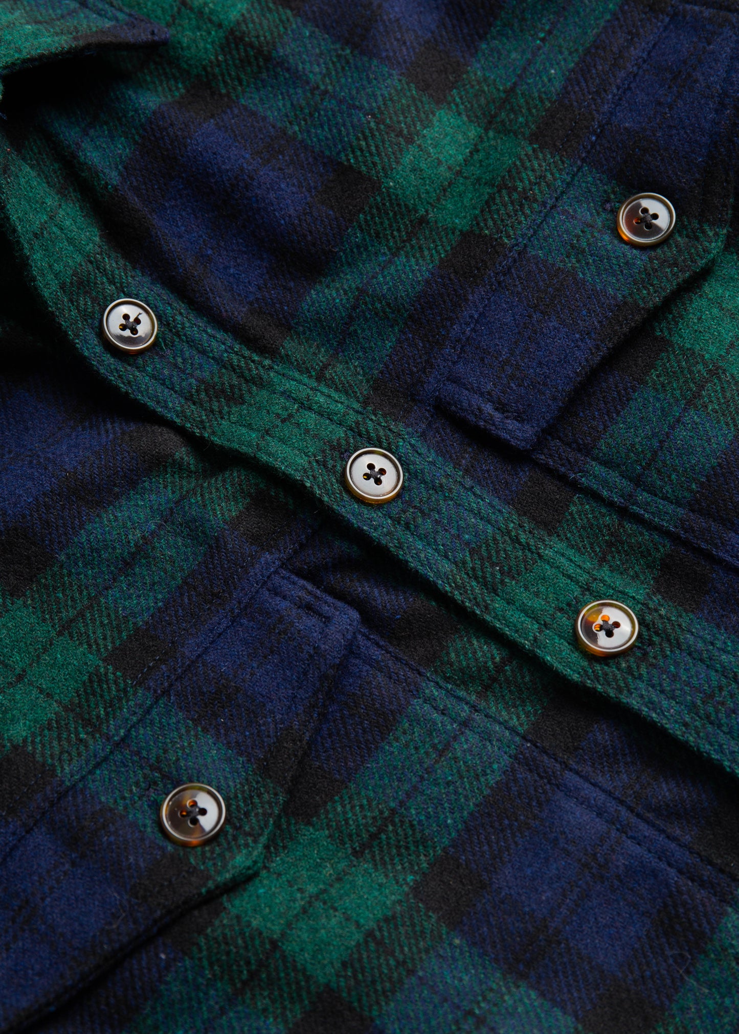 Close up of double pocket shirt jacket in color blackwatch wool buttons and fabric