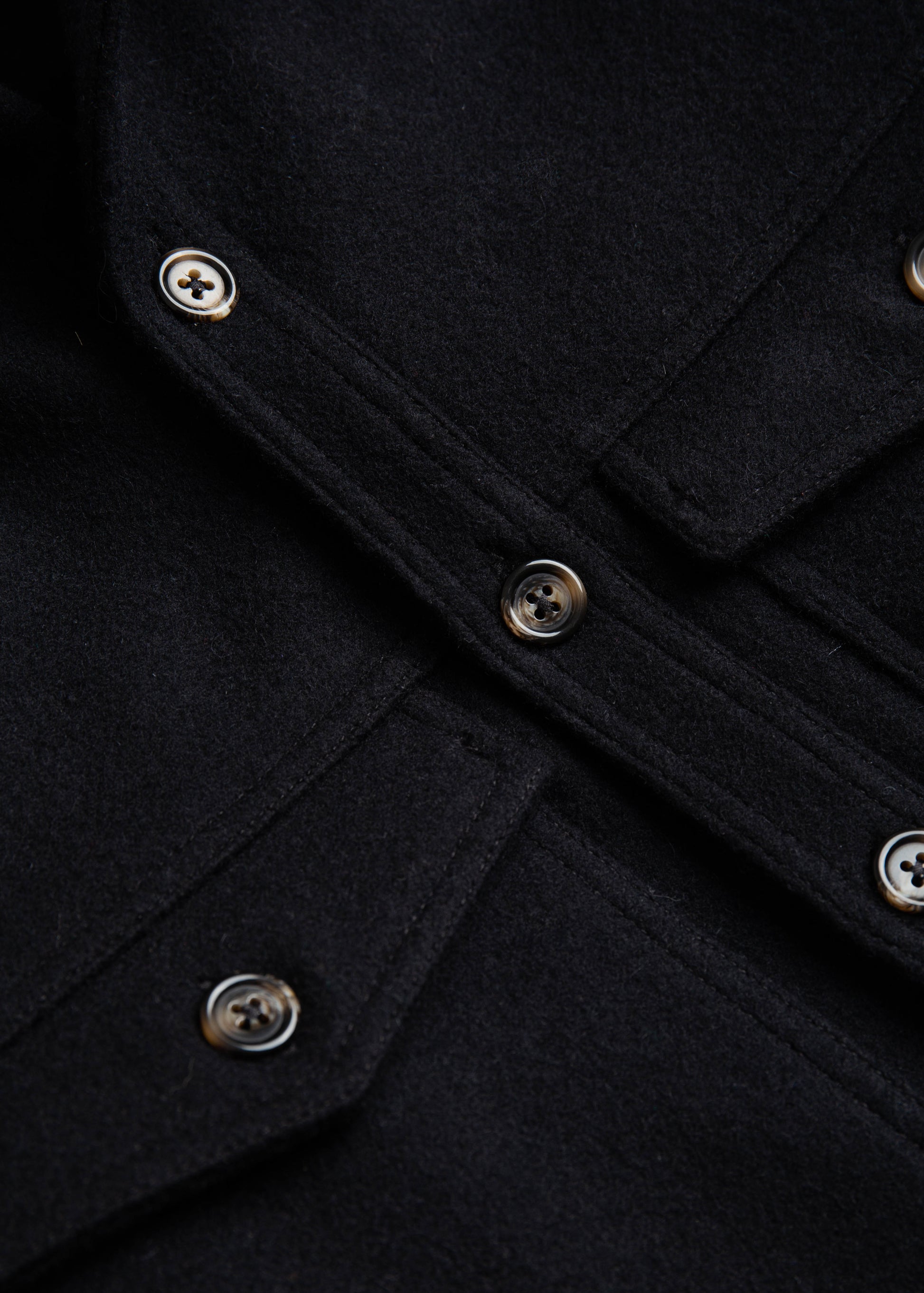 Front close up of buttons and fabric on the double pocket shirt jacket color black melton wool