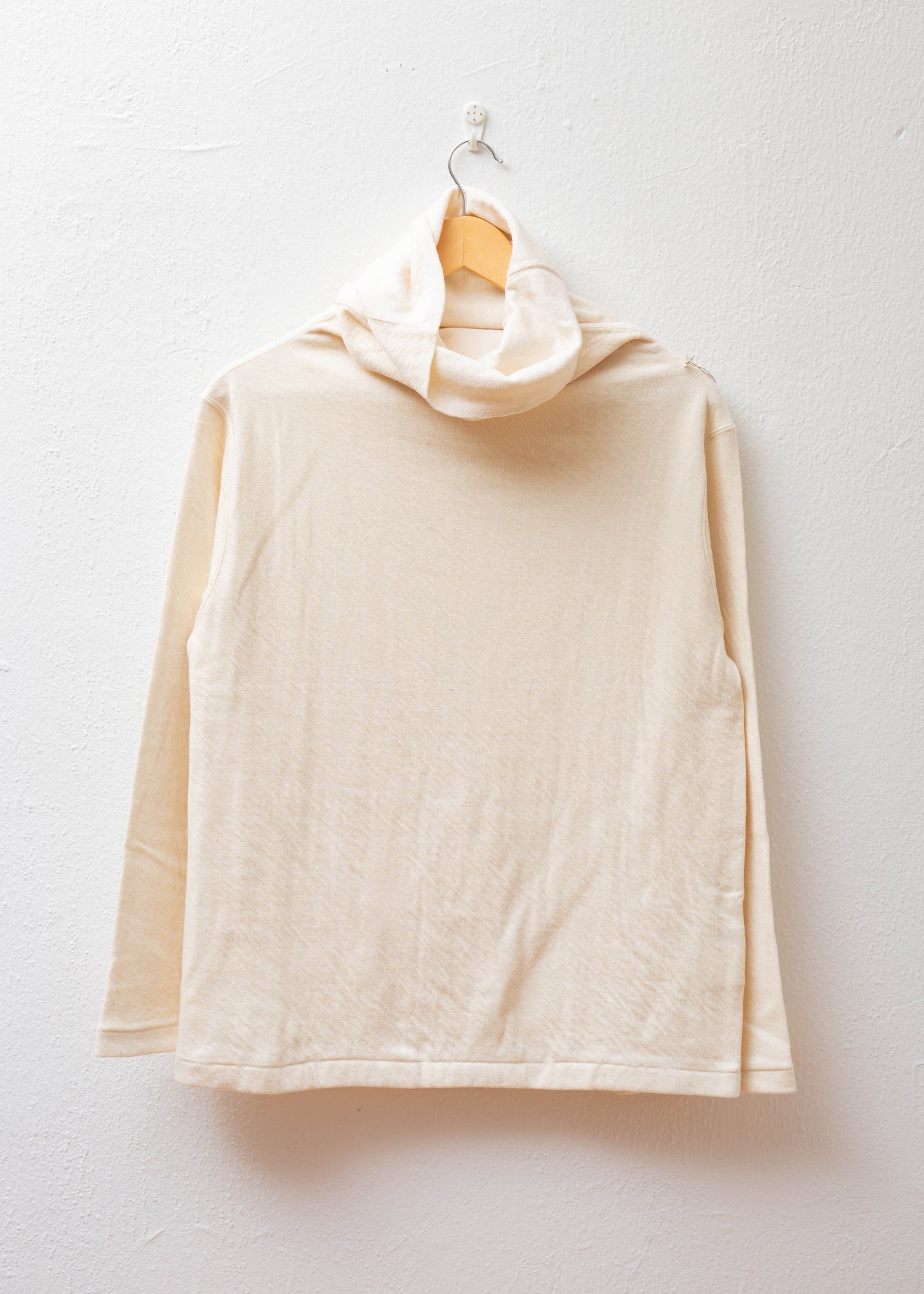 Turtleneck Pullover in color natural hanging on white wall