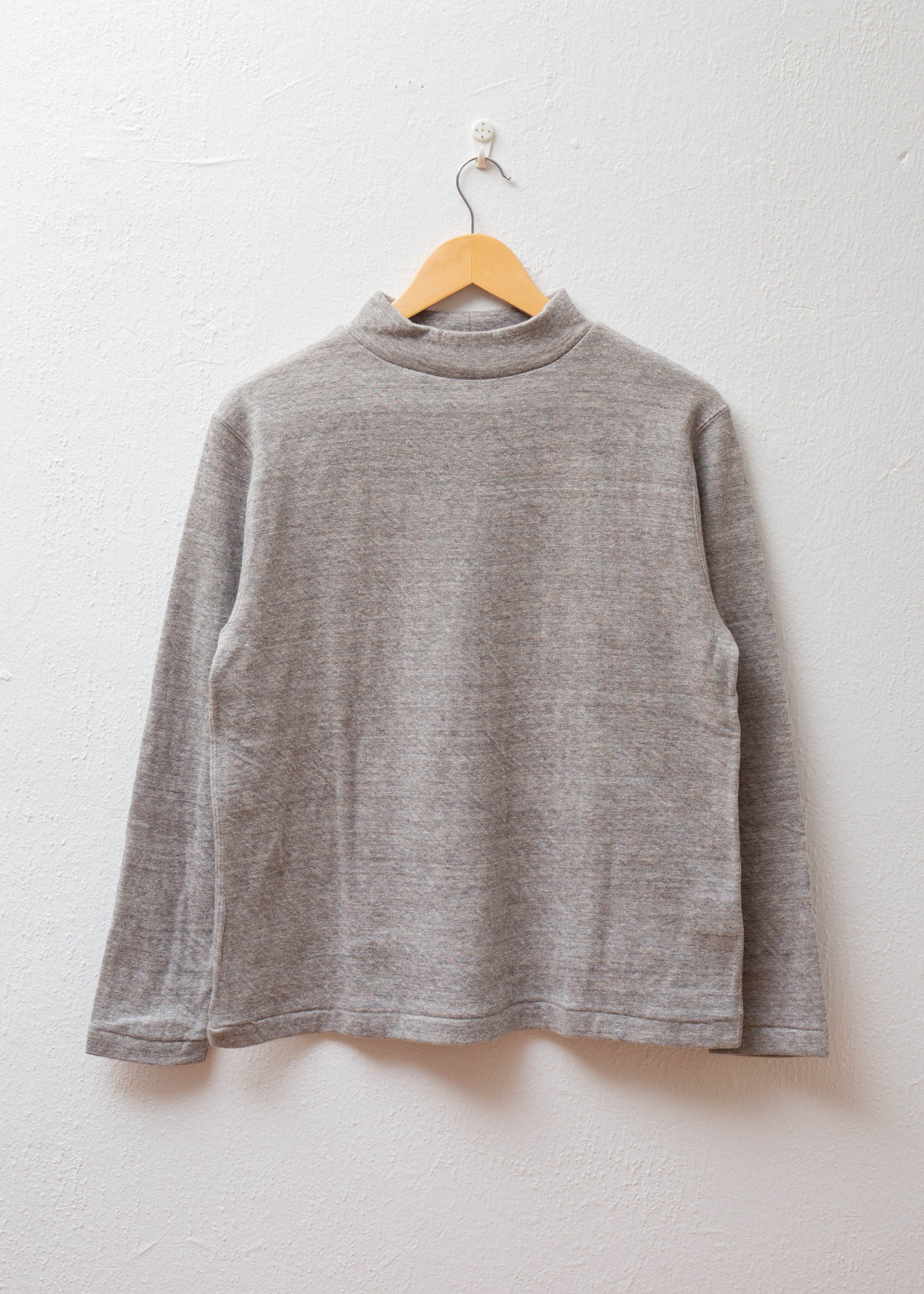 Mock Neck Pullover in color grey hanging on white wall
