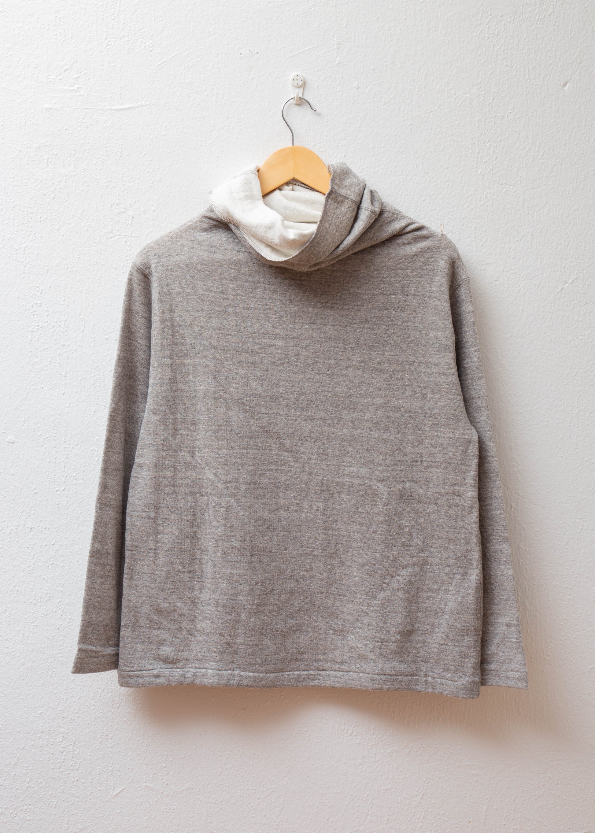 Turtleneck Pullover in color gray hanging on white wall