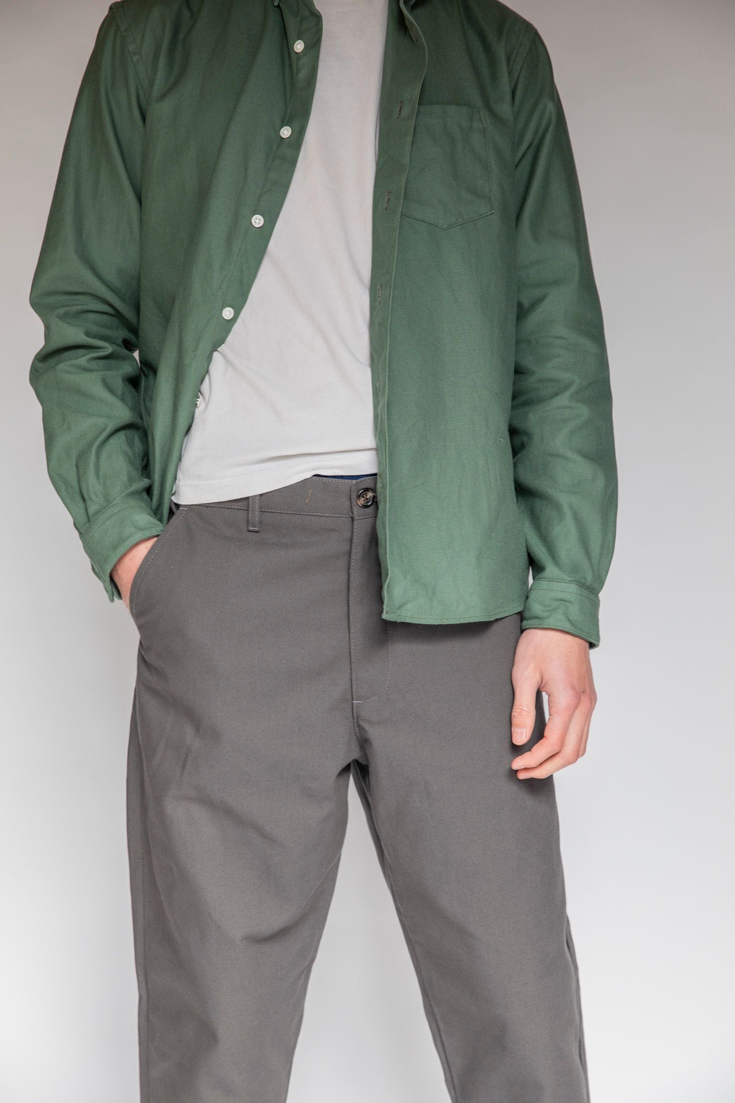Model standing up wearing Single needle shirt in bottle green canvas, white t-shirt and charcoal danver pants